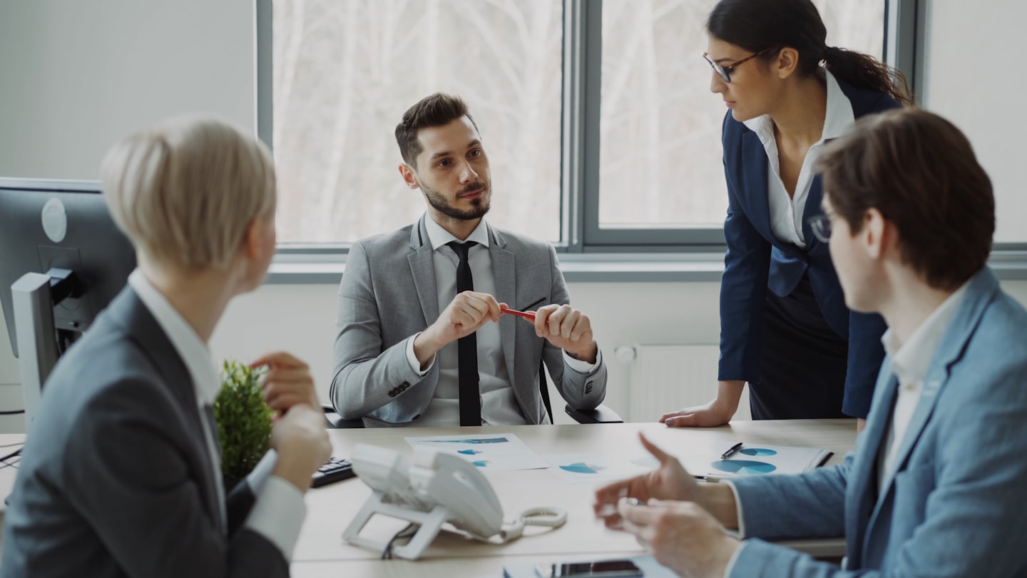 Profesionales de negocios discuten planes alrededor de una mesa de conferencias.